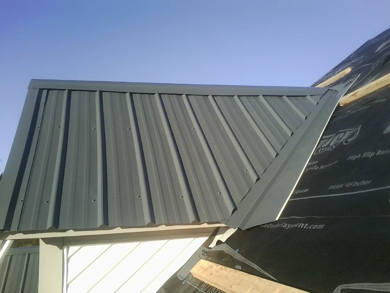Gray metal roof panels going on over a garage gable in West Creek