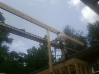 Carpenter setting a ridge beam over a new addition frame — Ice Dam Removal by Roofing Brothers in West Creek