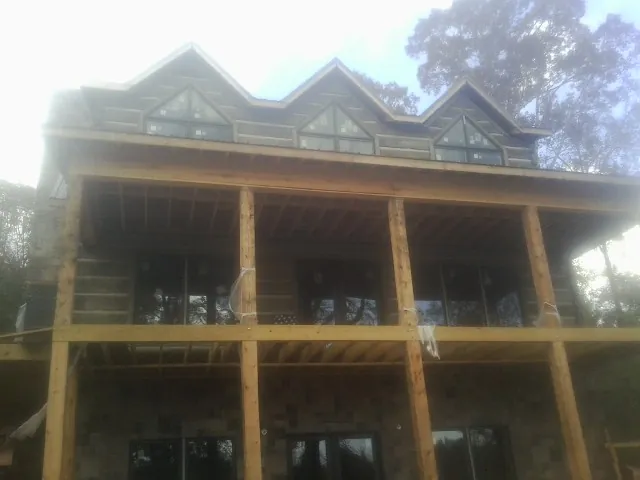 Dormers and porch framing on a large log home under construction — Roof Coating work by our crew in West Creek