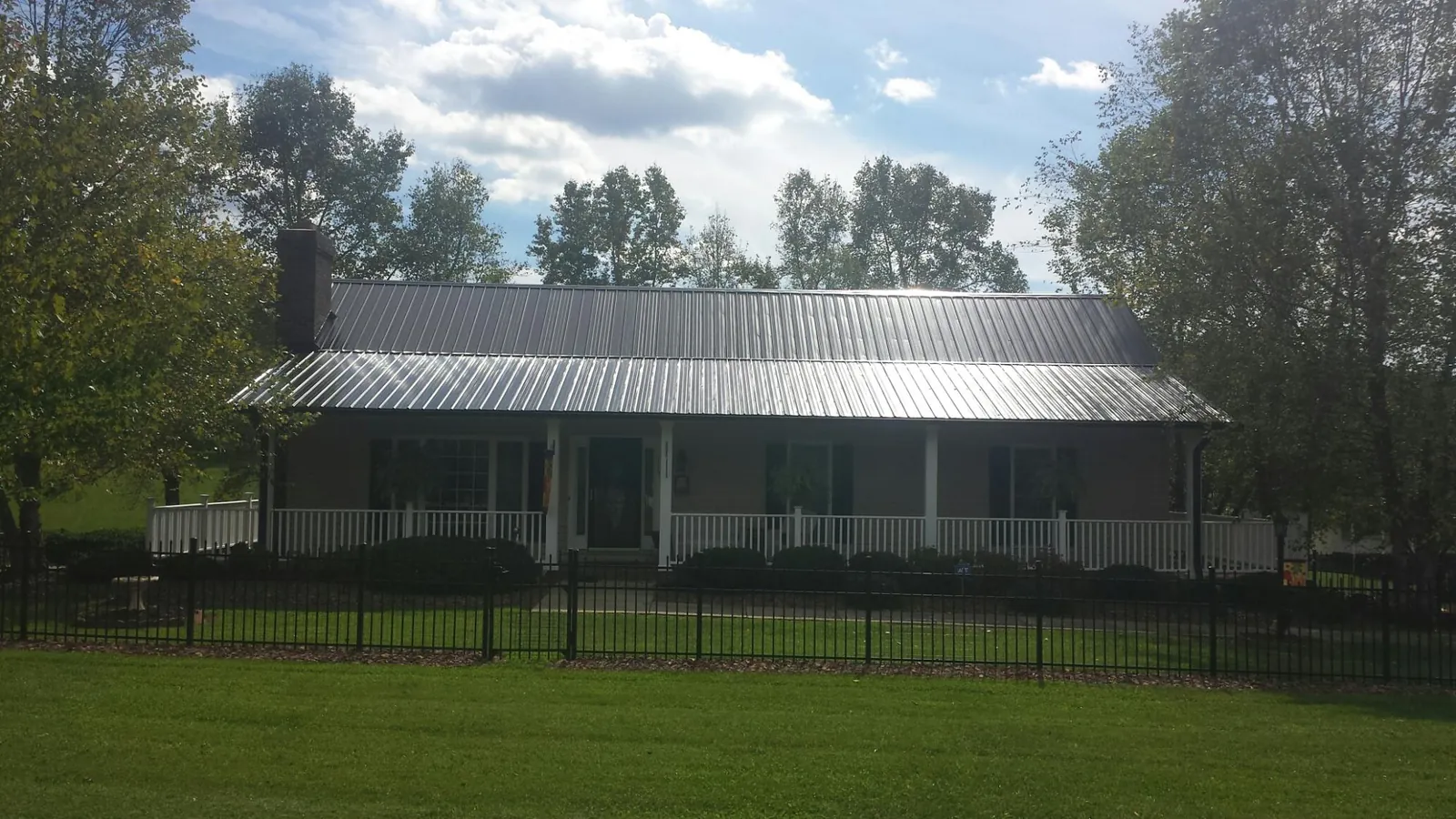 Gray metal roof on a brick ranch with a full width front porch — Gutter Guard Installation work by our crew in West Creek