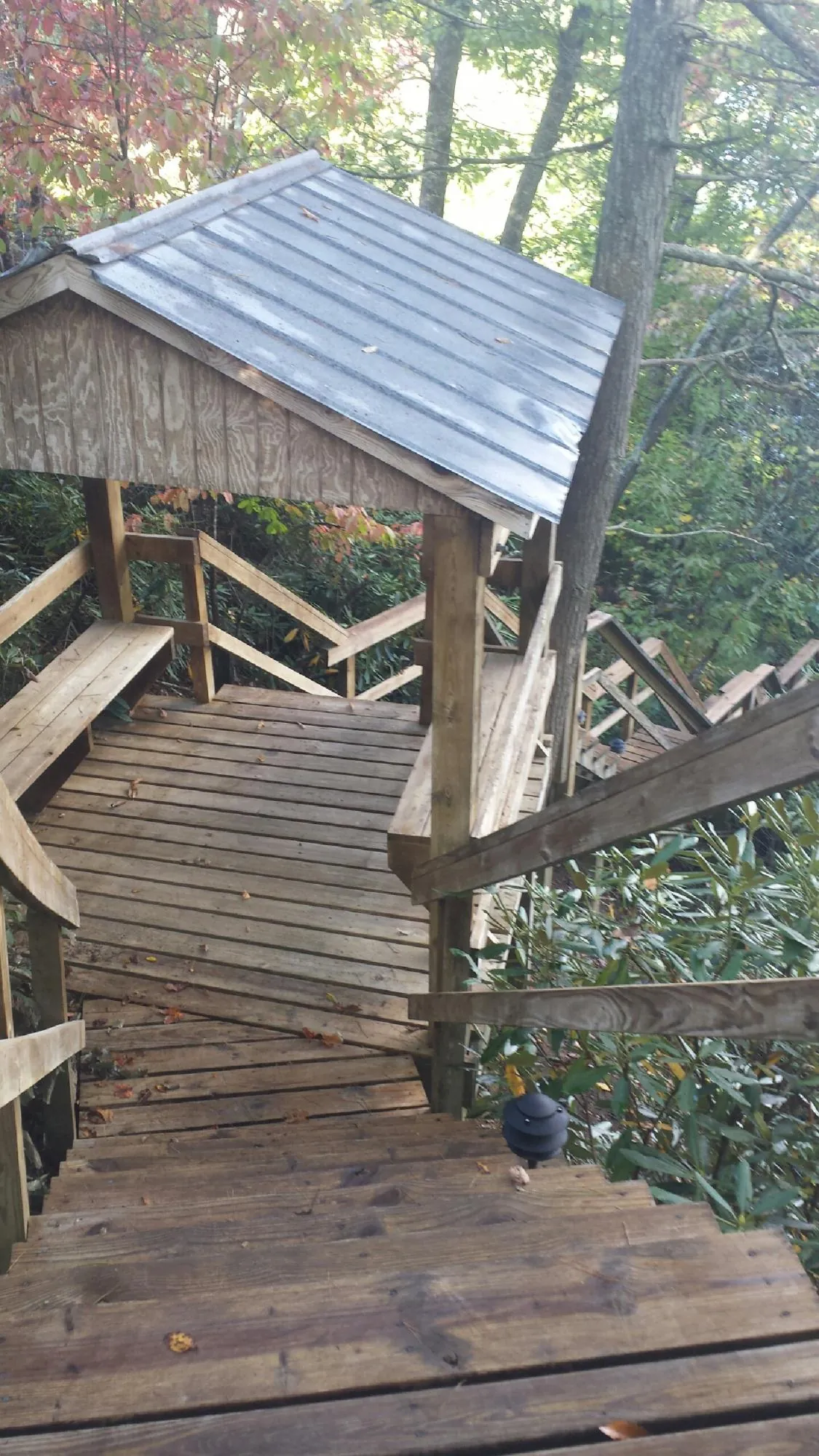 Metal roofed shelter over wooden steps on a wooded walkway — Skylight Repair & Installation work by our crew in West Creek