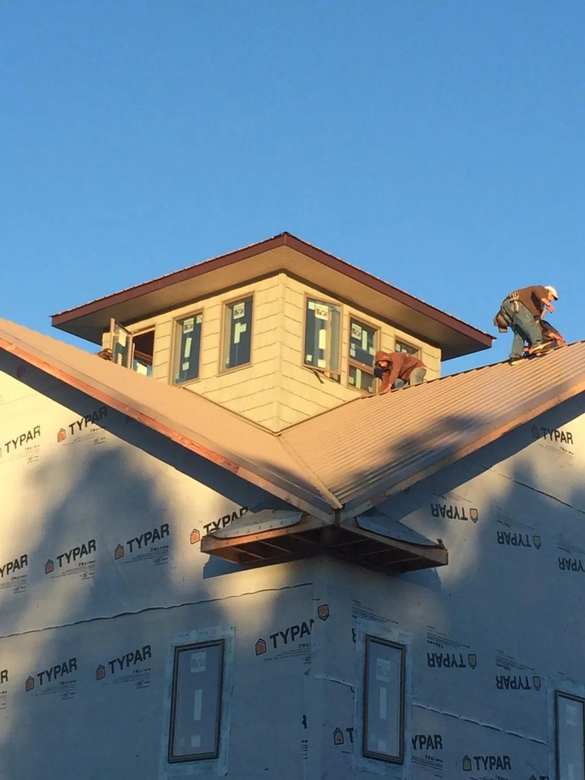 Roofers working around a rooftop cupola on a new metal roof at sunset — Roof Waterproofing in West Creek by Roofing Brothers